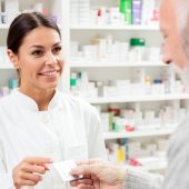 Beautiful young pharmacist selling medications to senior patient